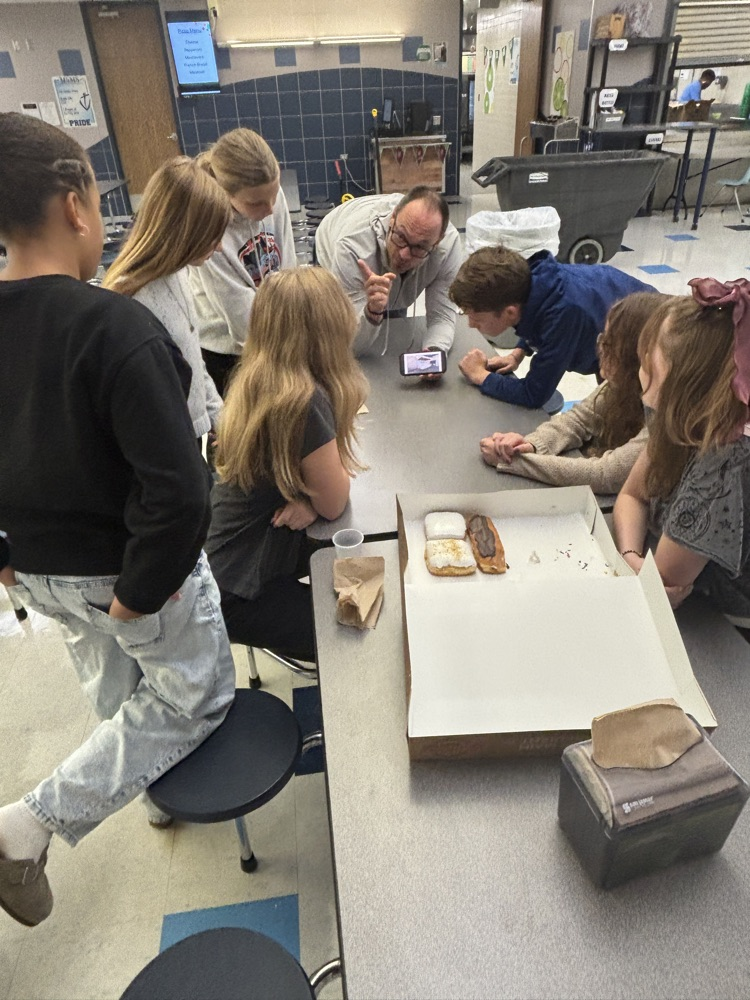 looking at photos of upcoming bond construction updates to the middle school while enjoying donuts with Mr. Ammeraal