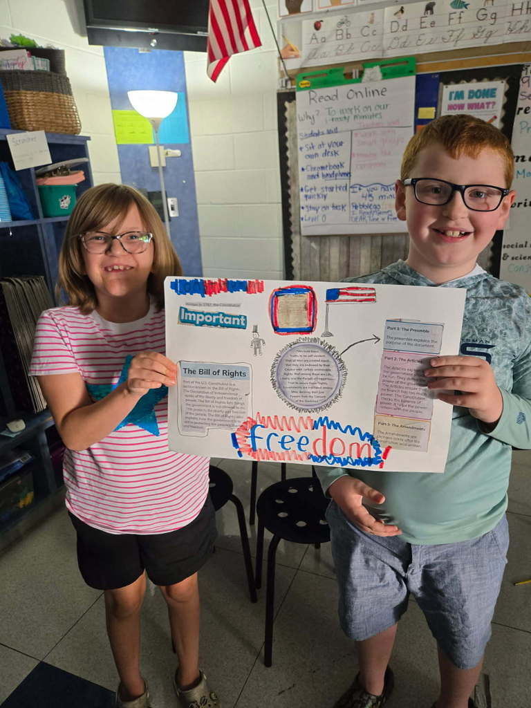 Two students proudly holding their constitution posters