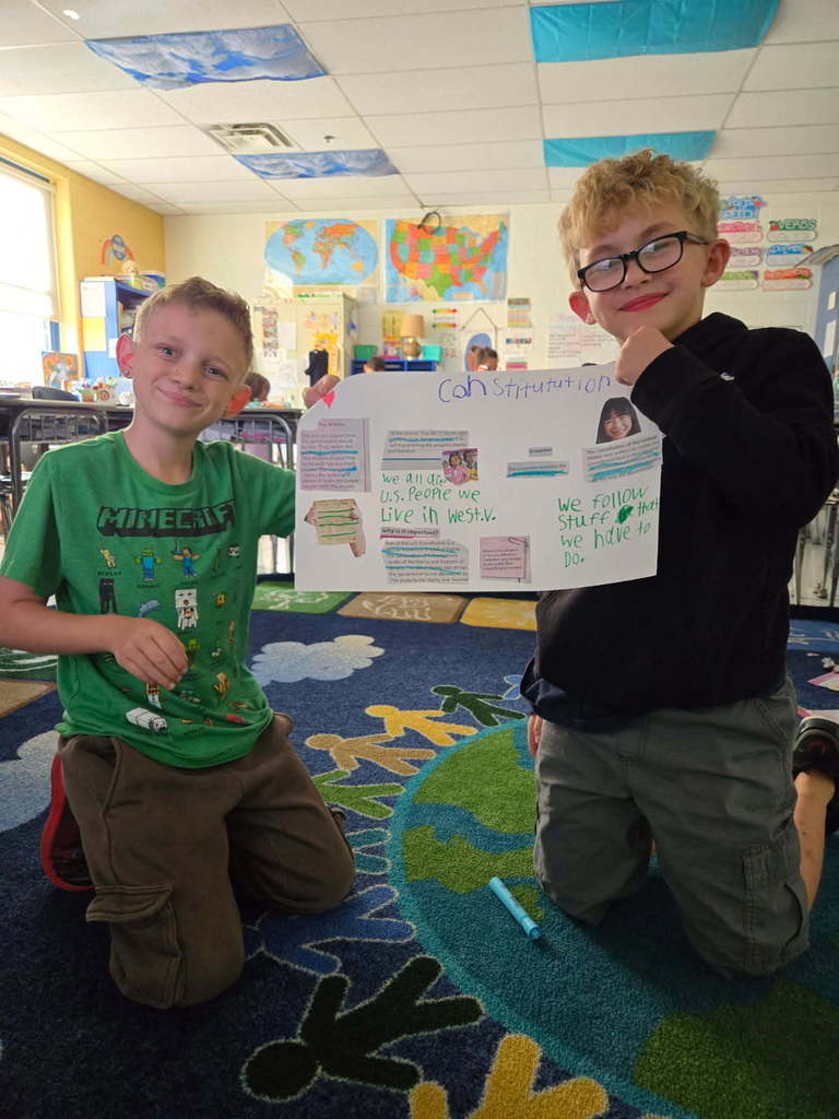 two third grade boys holding a constitition poster they created
