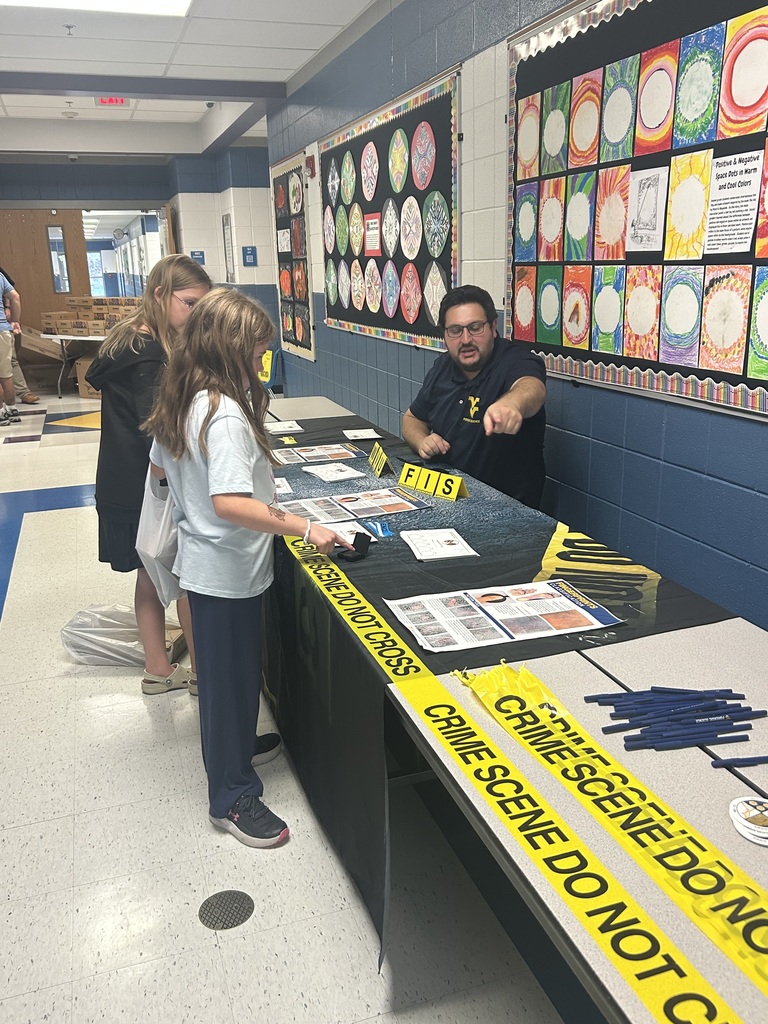 Two girls studying finger print patterns with WVU Crime Scene representative