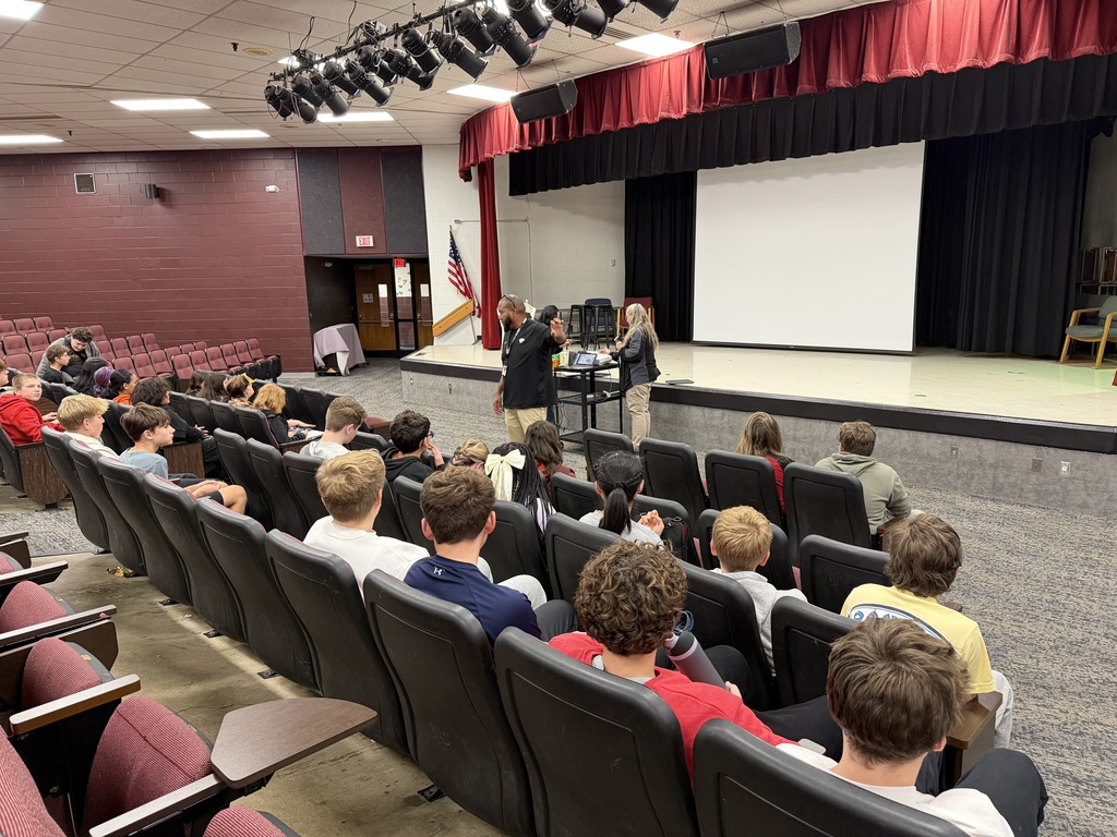 Presenter speaking to an auditorium of students