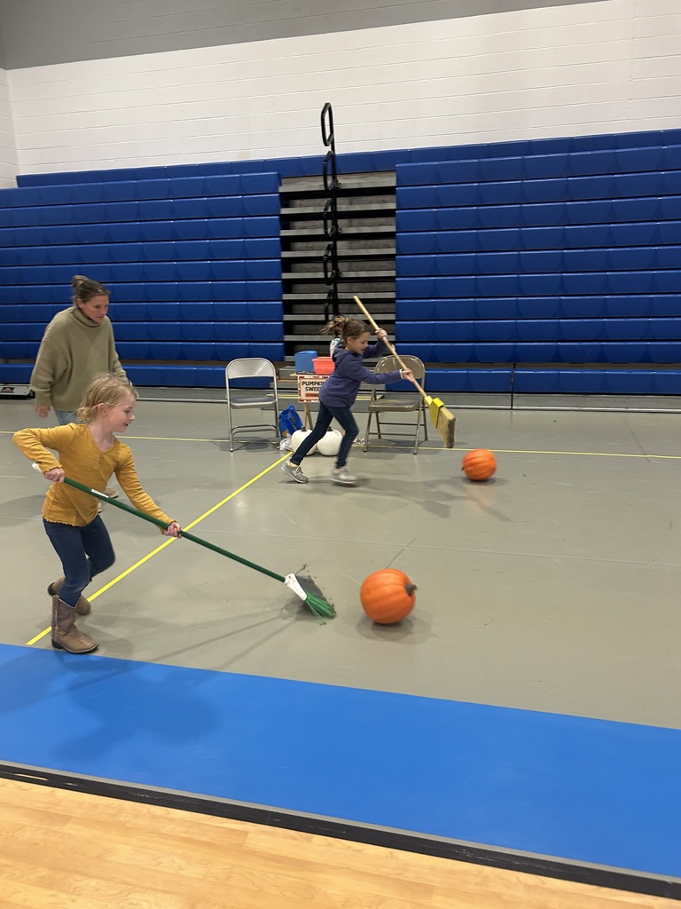two studetns pushing pumpkins with a brom in a relay race
