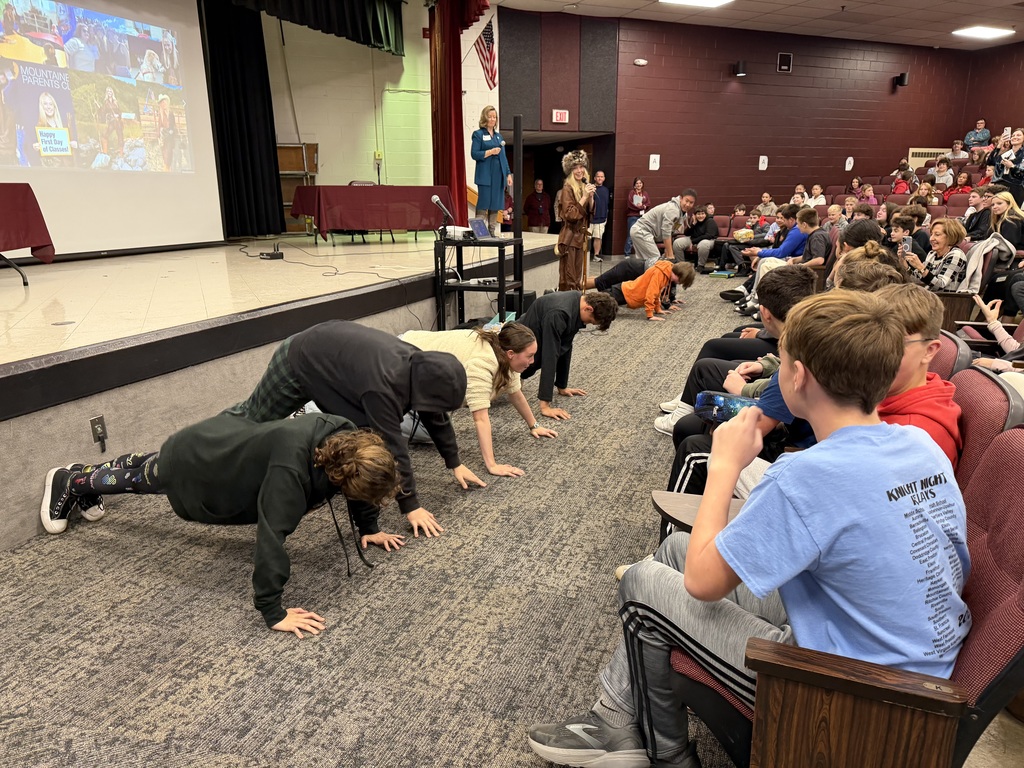 students in an auditorium while some are doing push ups