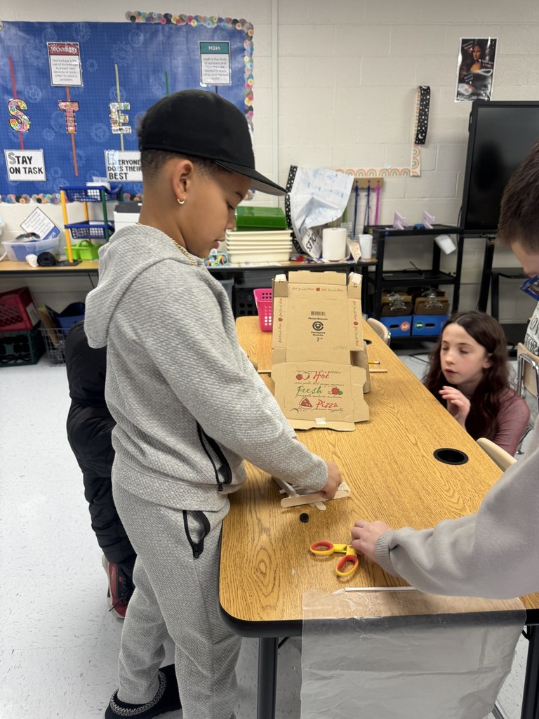 In the STEAM Lab making a sled run. Students had to design an incline that would allow their sled to complete the run and keep their snowman parts and people inside the sled. They measured the distance their sled ran.