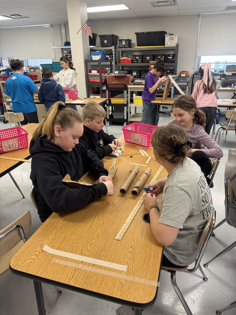 In the STEAM Lab making a sled run. Students had to design an incline that would allow their sled to complete the run and keep their snowman parts and people inside the sled. They measured the distance their sled ran.
