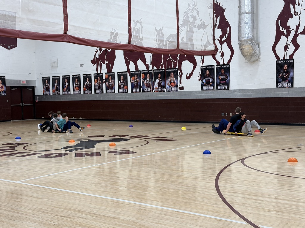 Students racing scooters in the gym
