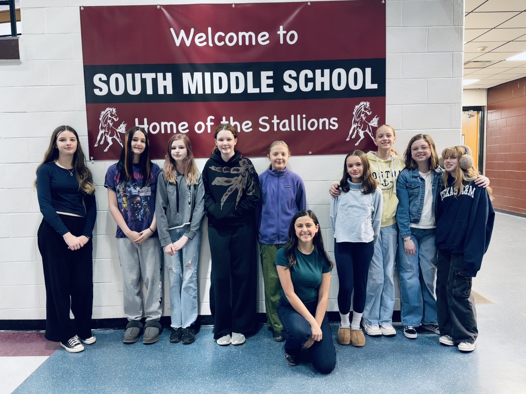 Girls standing in front of a school banner