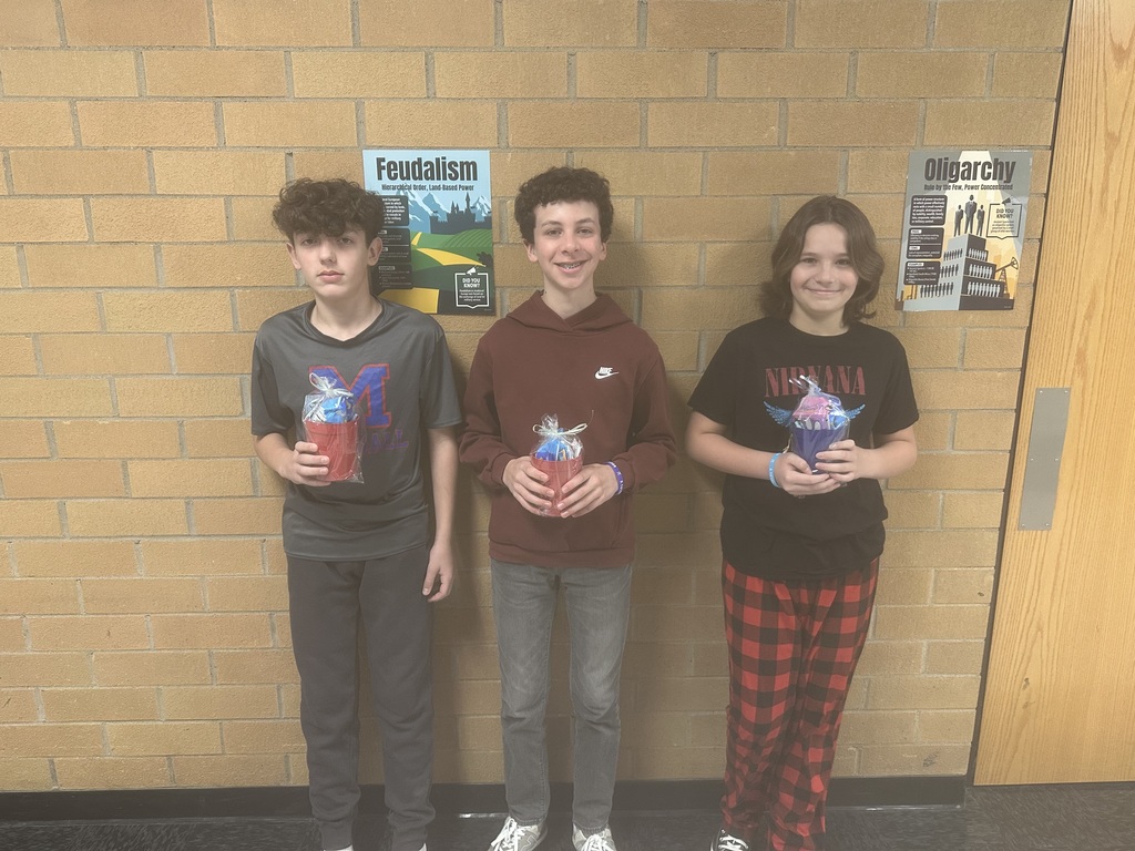 Students holding a winning cup with prizes in it