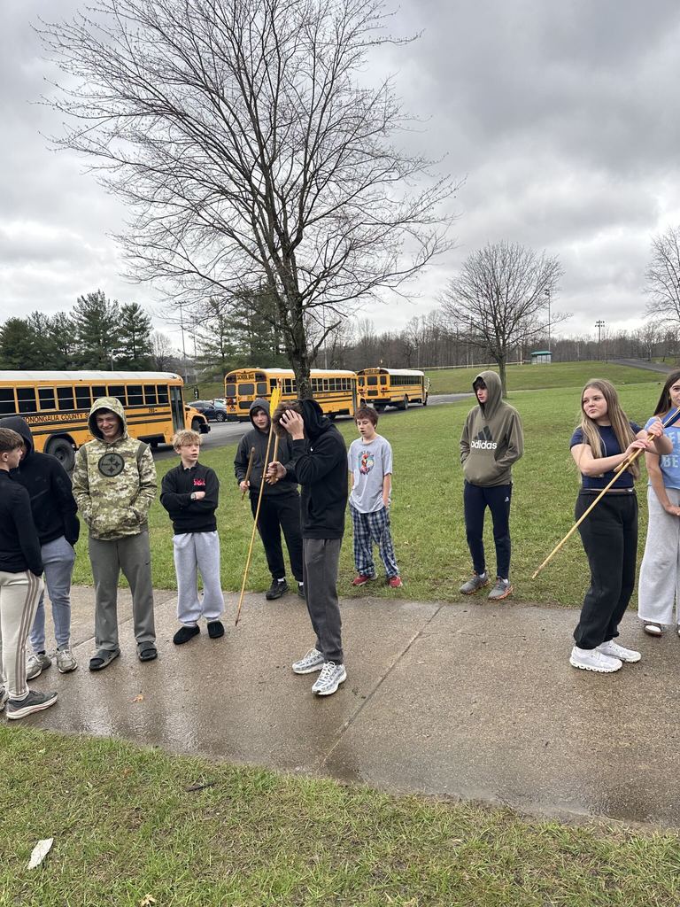group of students outside and 2 are holding an arrow