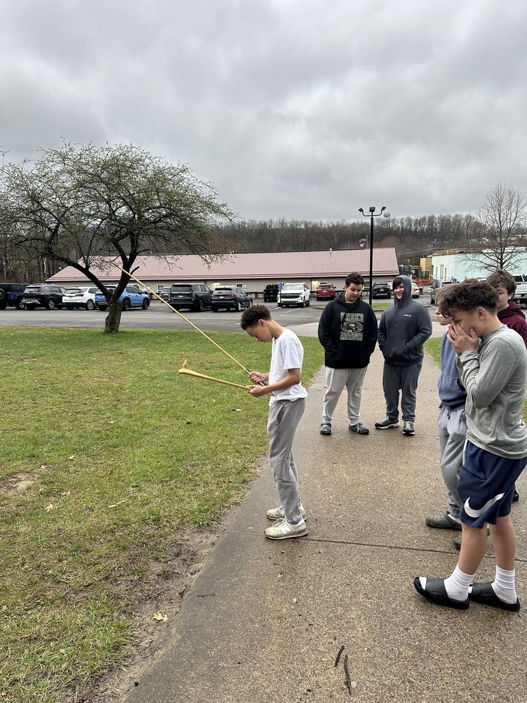 students standing outside and a boy holding an arrow