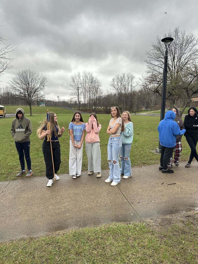 Group of students standing outside and a girl holding an arrow