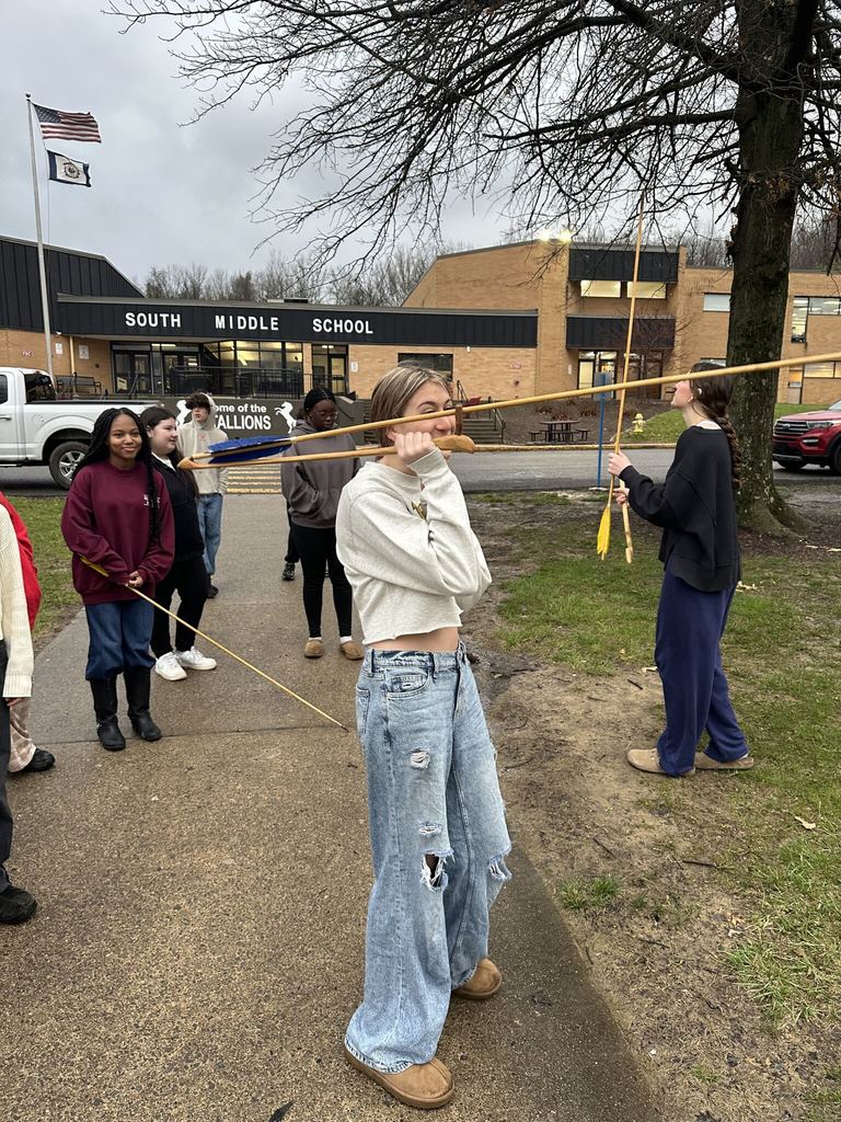 students standing outside a few are holding arrows