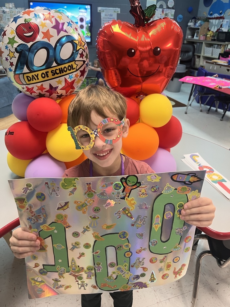 PreK student in front of balloons celebrating 100 days with a poster project!