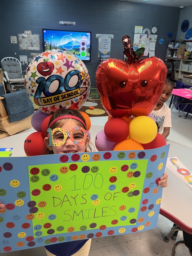 PreK student in front of balloons celebrating 100 days with a poster project!