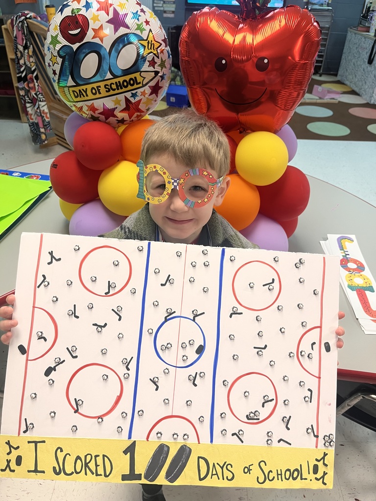 PreK student in front of balloons celebrating 100 days with a project. 