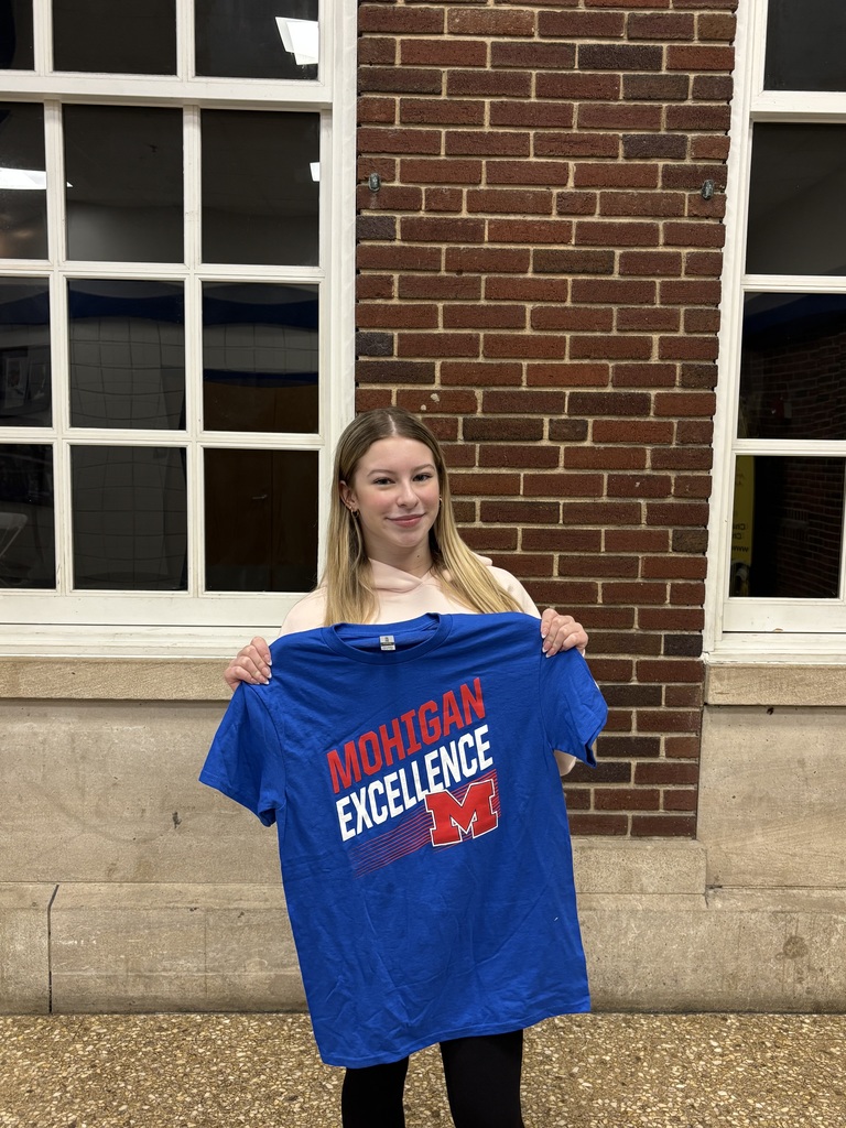 Girl holding a tshirt in front of a brick wall