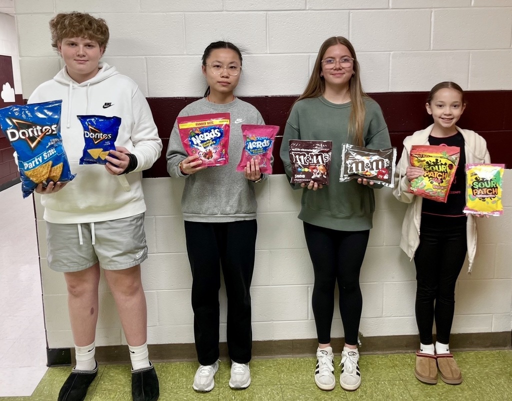 4 students holding up bags of chips and candy. They made a duplicated bag in art class. These are the winners.