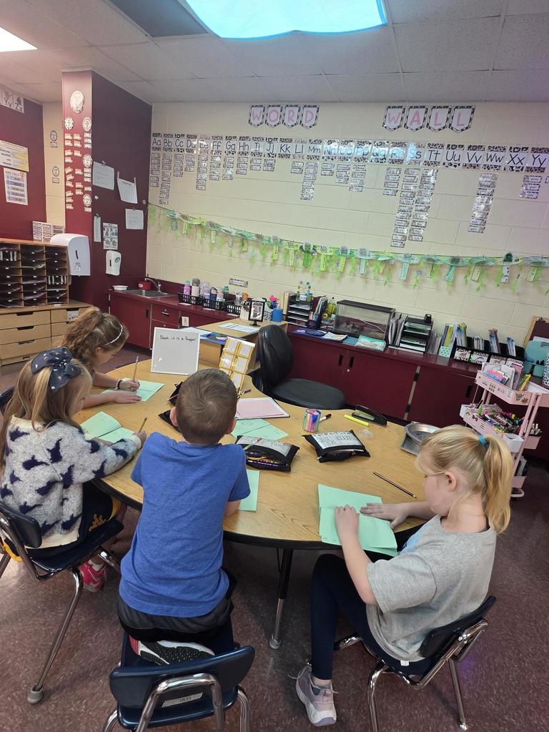 Kindergarten students writing in books