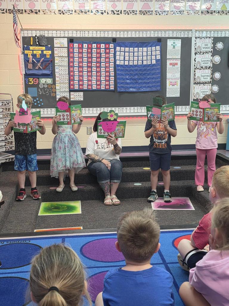 Kindergarten students reading about frogs with book in front of faces