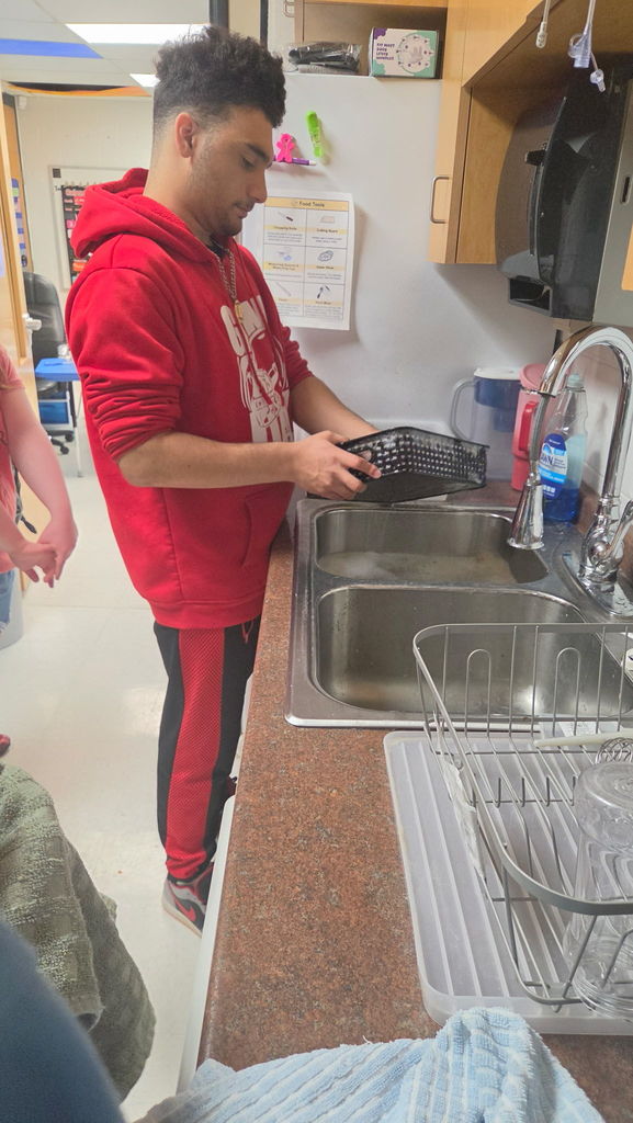 A male standing at the sink with a basket.