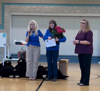 Principal Hartshorn with a microphone and  Teacher Karen Davis holding pink flowers. Karen Davis named West Virginia's Enviornmental Teacher of the Year 