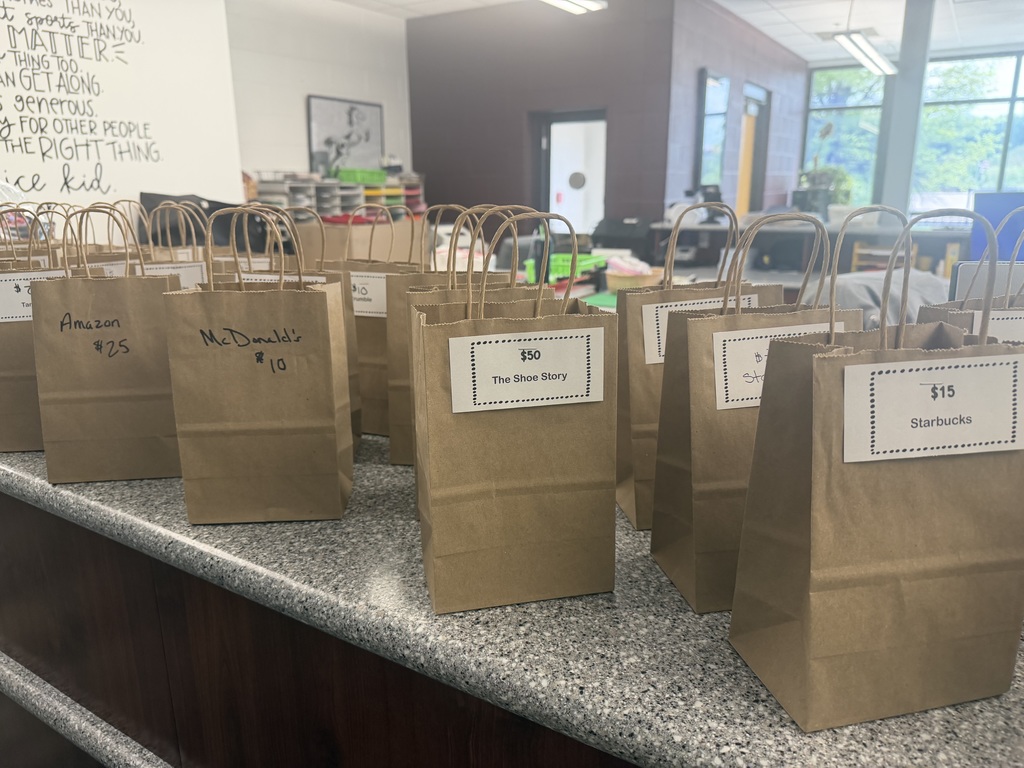 Brown bags sitting on a counter with various businesses and amounts on them.