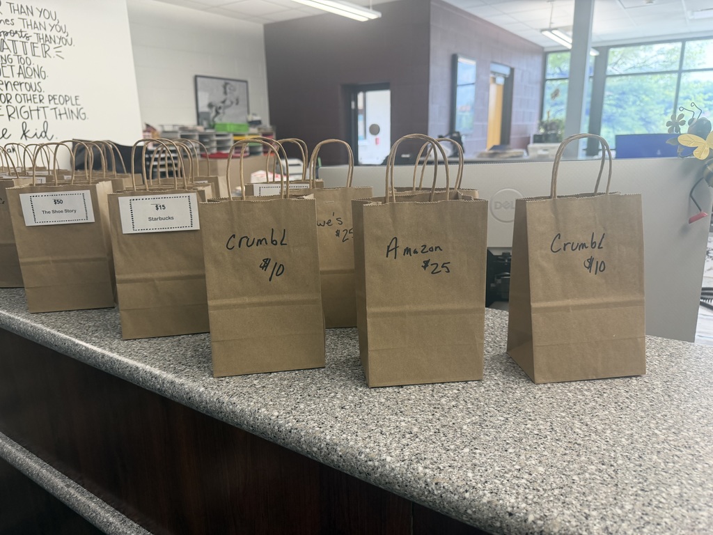 Brown bags sitting on a counter with various businesses and amounts on them.