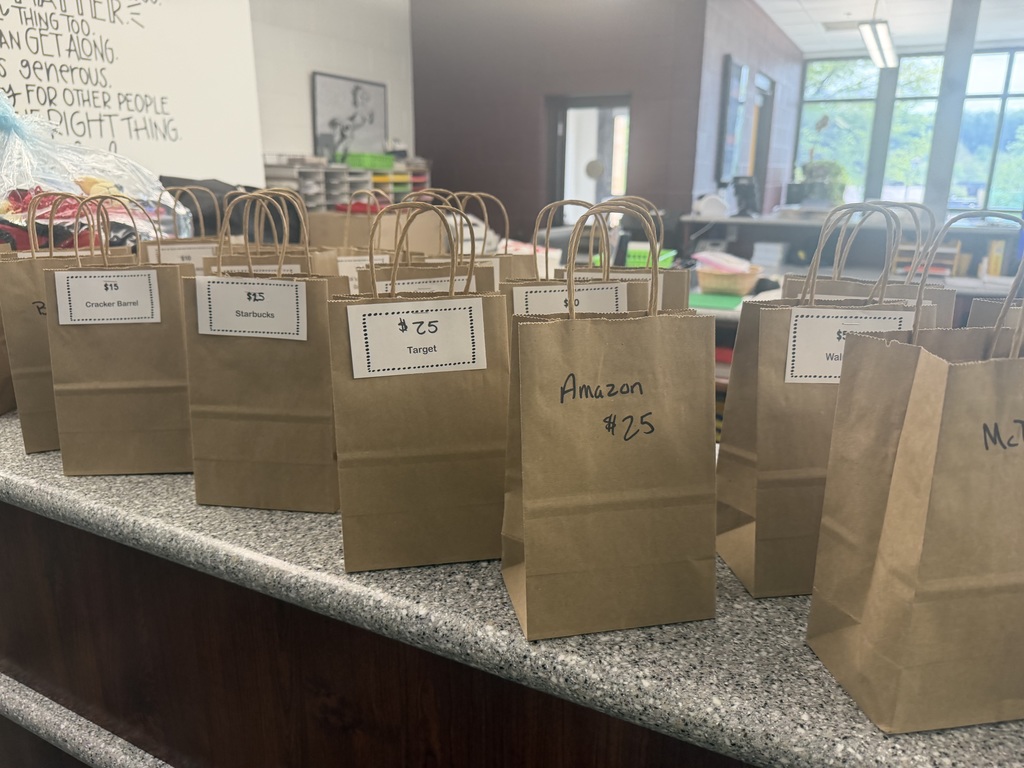 Brown bags sitting on a counter with various businesses and amounts on them.