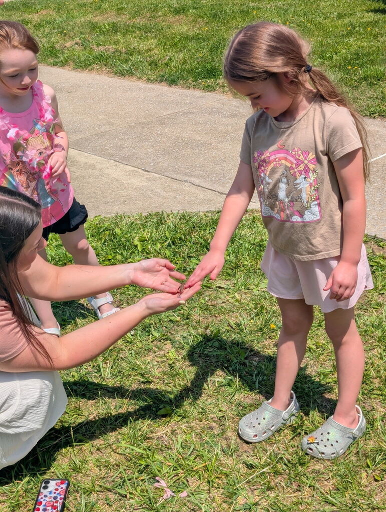 Student holding a butterfly with teacher