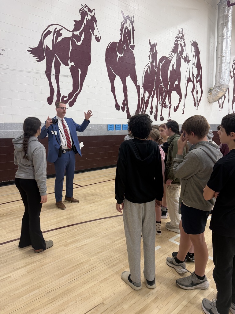 A dressed up man is talking to a group of students