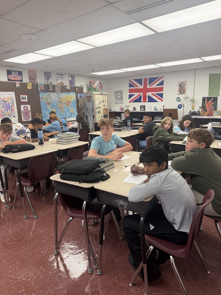 students sitting at desks in a classroom. A British flag in hanging on the back wall.