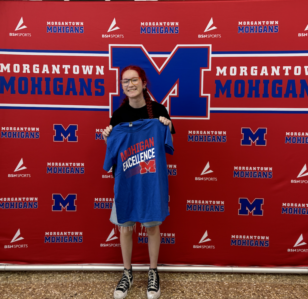 Student standing infront of a background with tshirts