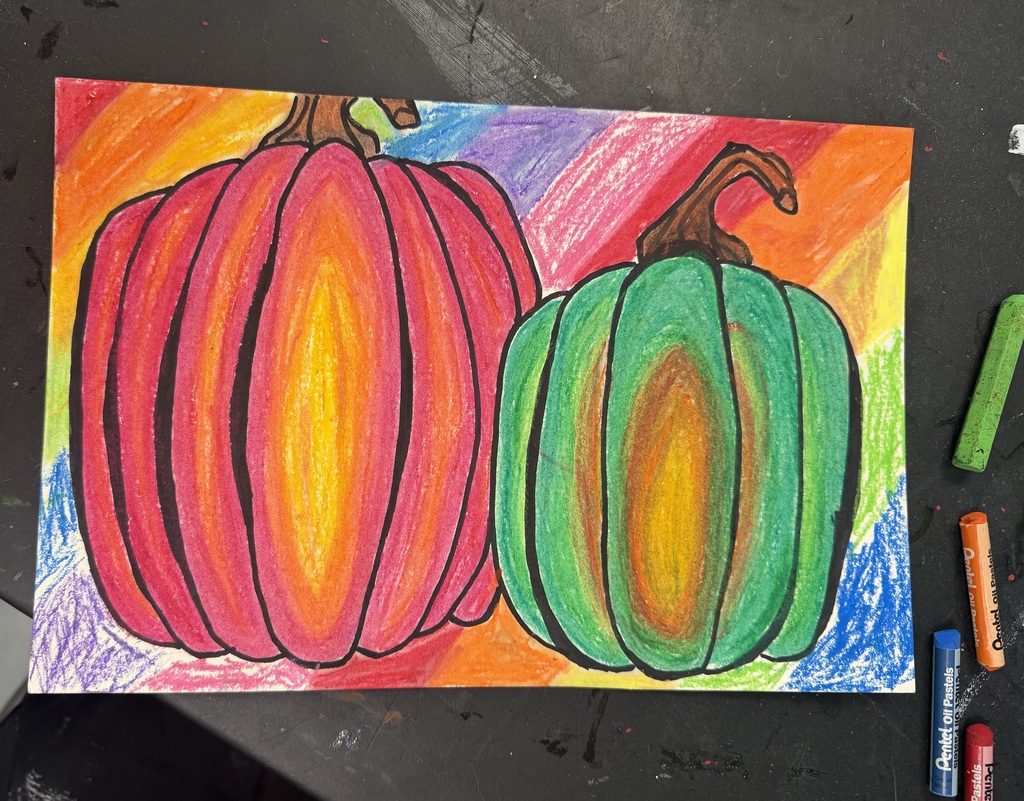 A piece of paper with 2 oil pastel pumpkins on it. One is orange and yellow and the other is green and yellow. There are 4 oil pastels to the right side of the painting.