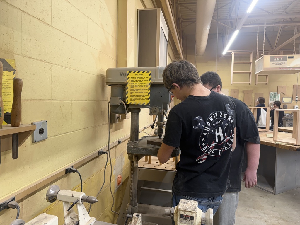 2 students standing at a piece of equipment in a workshop.