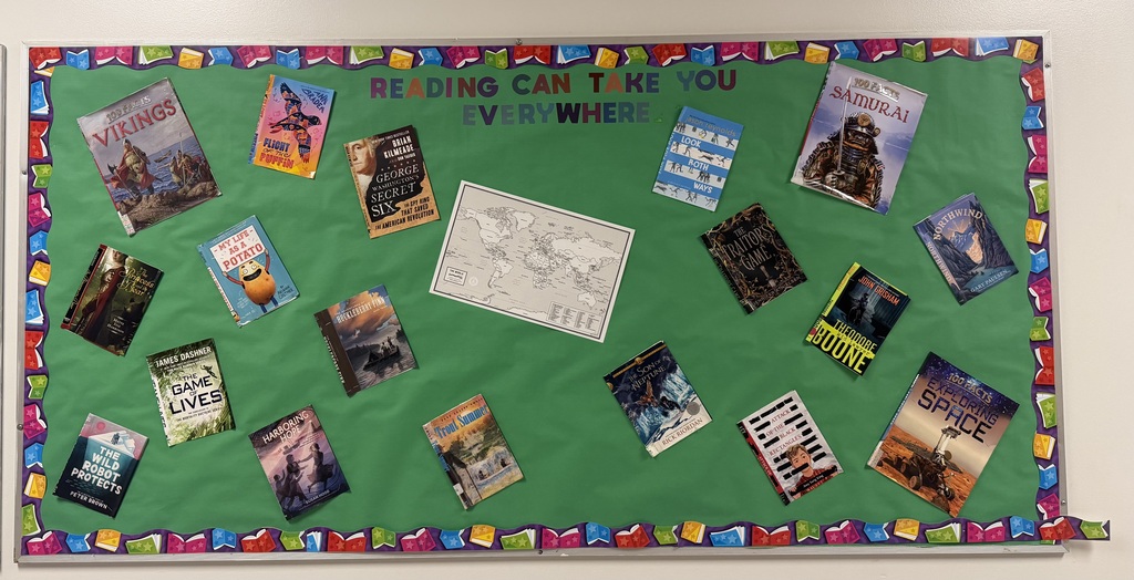 A green covered bulletin board with book covers and a map on it that says Reading Can Take You Everywhere. The bulletin board has a border around it that is books.