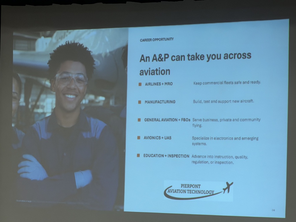 A slide being projected with a person wearing safety googles arm and that has his arms crossed. The rest of the slide is all text.