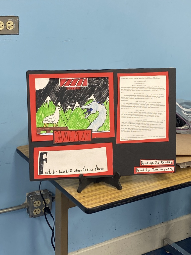 A photo of a piece of black paper with a drawing and text on it sitting on the corner of a table.