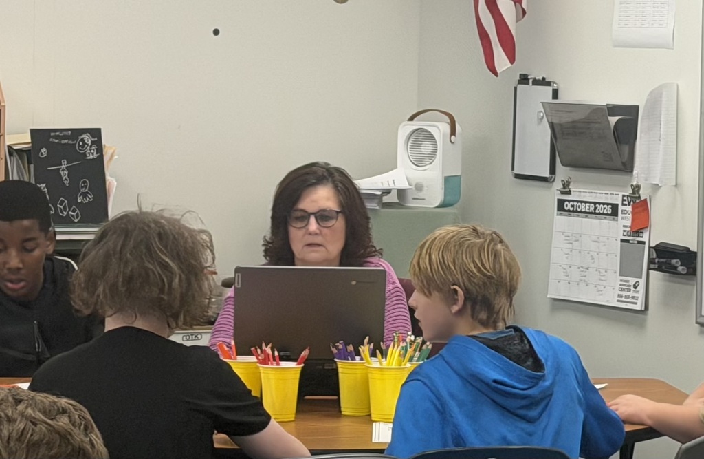 A teacher sitting at a table with 3 students.