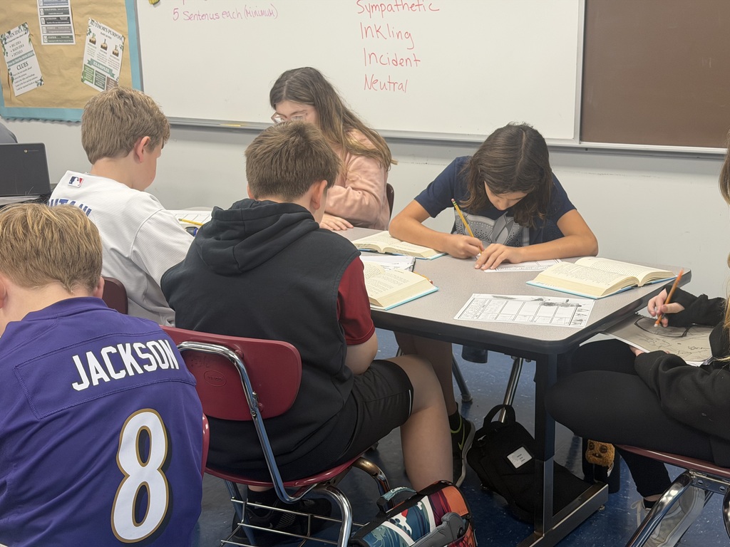 A photo of a group of students working at a table in a classroom.