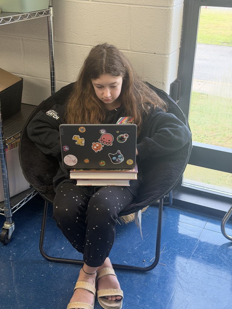 A girl sitting in a chair with a Chromebook