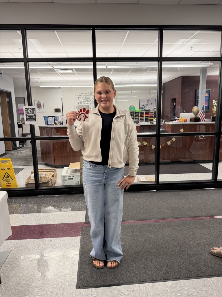 A photo of a girl holding a gift card standing in a school.