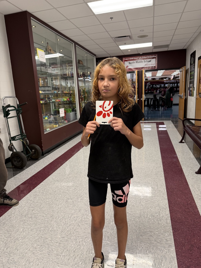 A photo of a girl holding a gift card in the hallway of a school