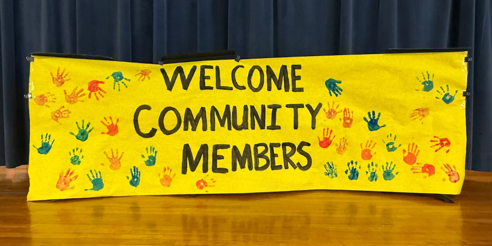 Yellow banner with painted hands that says, "Welcome Community Members"