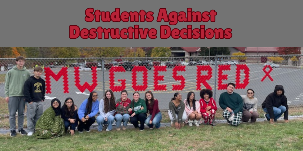 students kneeling on ground above red letters