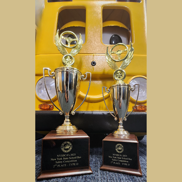 two trophies in front of a yellow cartoon bus 