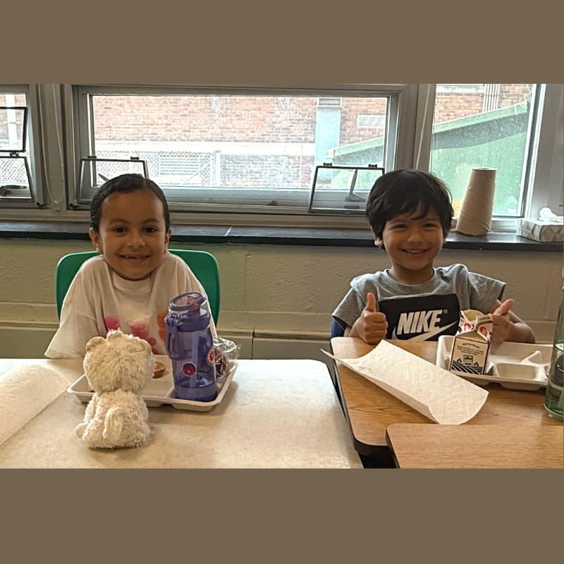 two students sitting at a lunch table eating breakfast