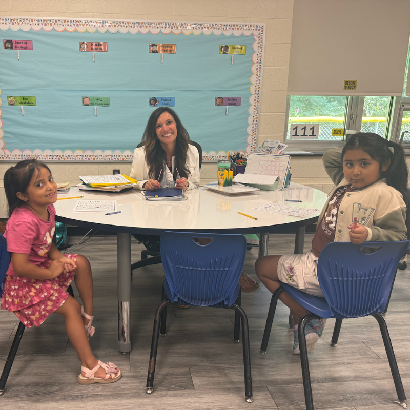 students and teacher sitting at a table writing