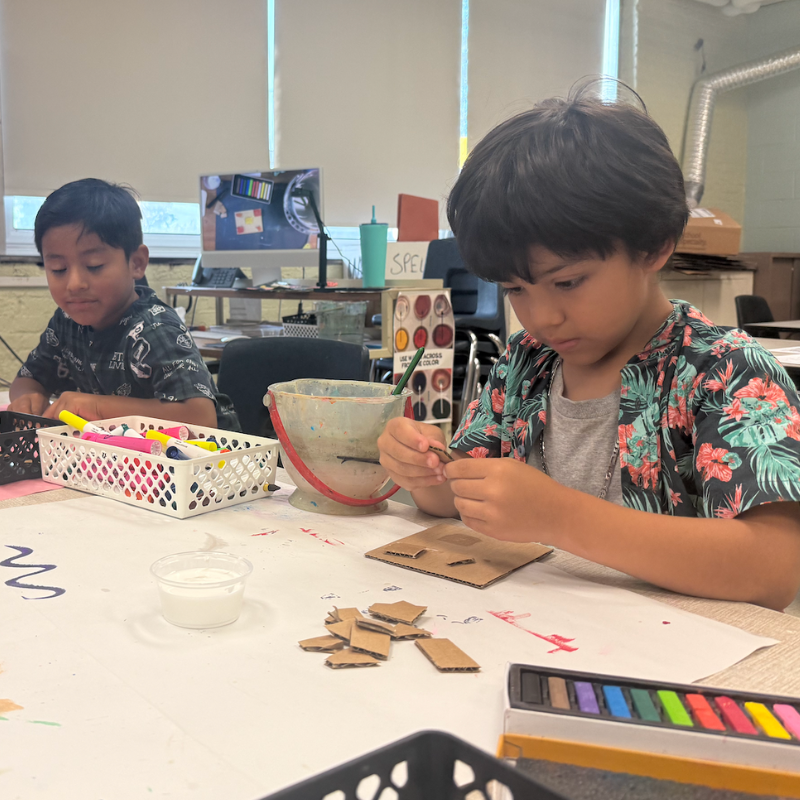 two students sitting at an art table