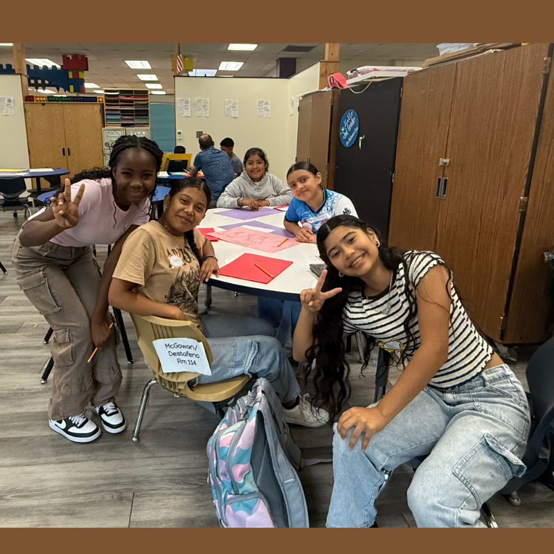 five students sitting at a table in a classroom