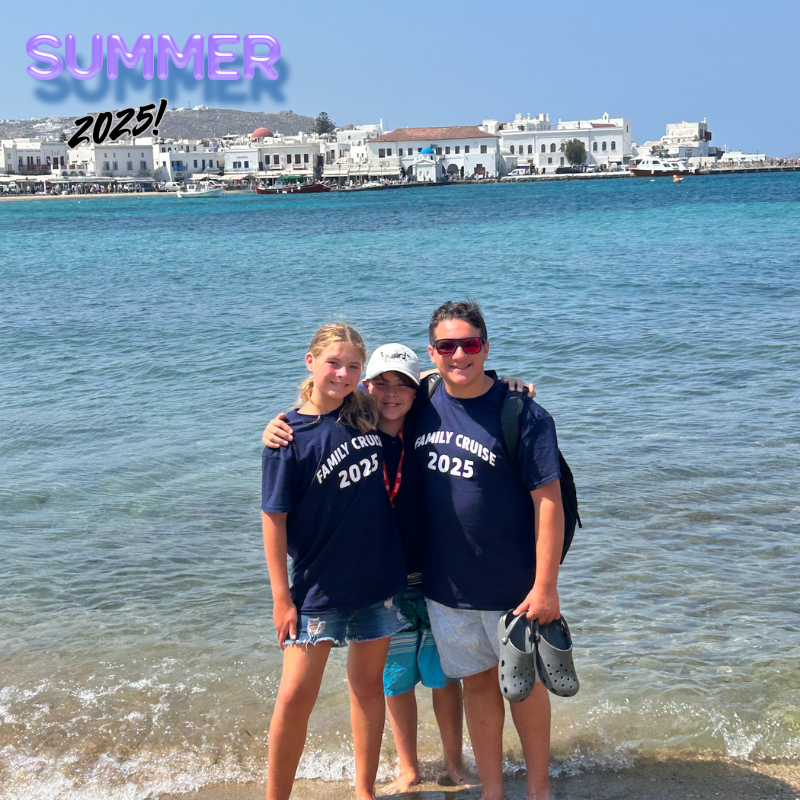 three students with blue shirts standing on a beach 
